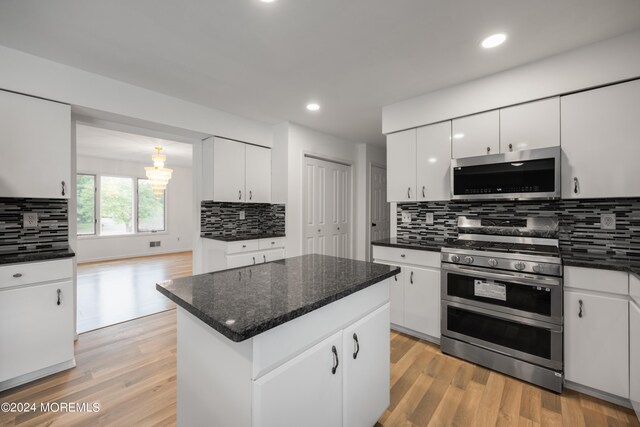 kitchen with decorative backsplash, white cabinets, stainless steel appliances, a center island, and light hardwood / wood-style flooring