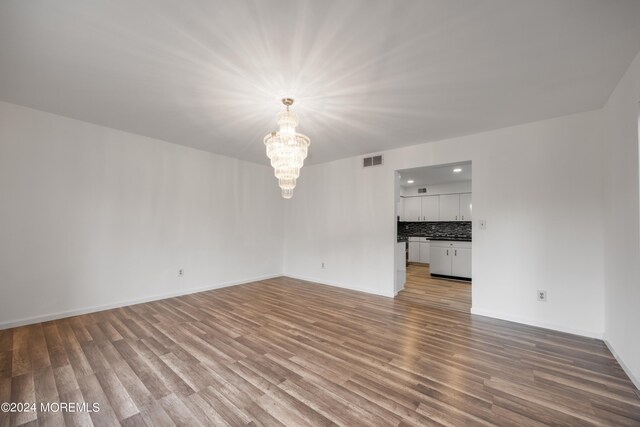 unfurnished living room featuring light hardwood / wood-style flooring and a notable chandelier