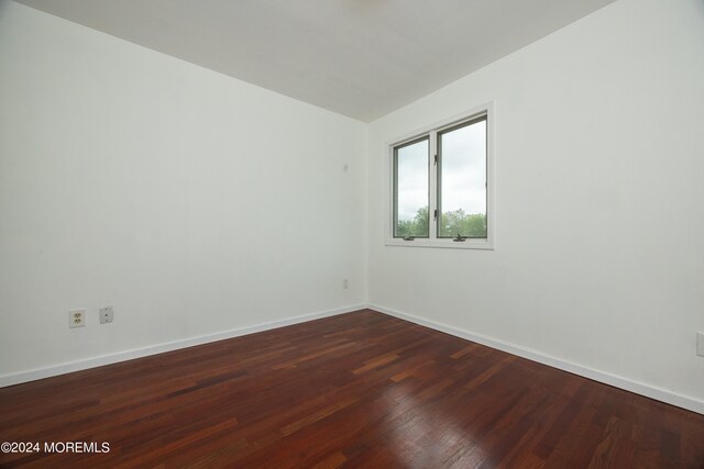 empty room with dark hardwood / wood-style flooring