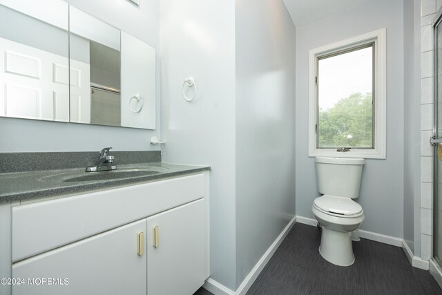 bathroom with tile patterned flooring, an enclosed shower, vanity, and toilet