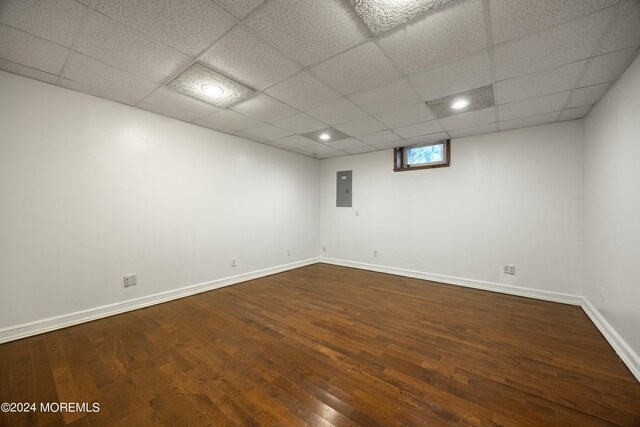 empty room with electric panel, a paneled ceiling, and hardwood / wood-style floors