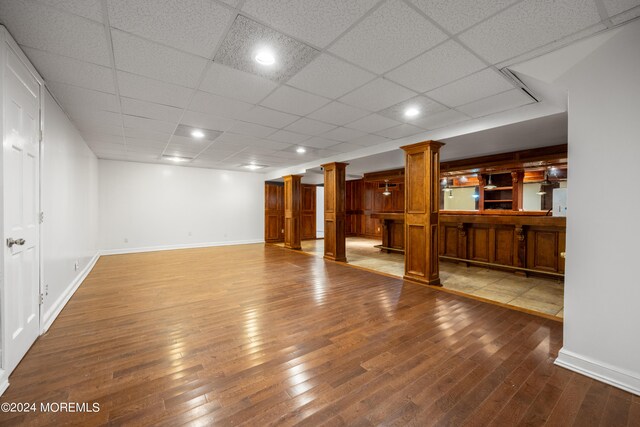 interior space featuring hardwood / wood-style floors, ornate columns, and a paneled ceiling