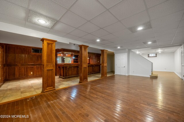 basement with a drop ceiling and hardwood / wood-style flooring