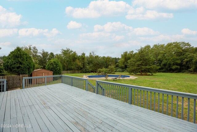 wooden deck featuring a storage shed and a lawn