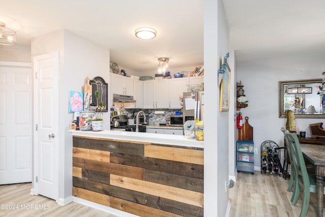 kitchen with white cabinets, backsplash, appliances with stainless steel finishes, and light wood-type flooring