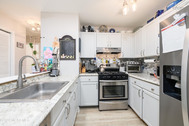 kitchen featuring appliances with stainless steel finishes, white cabinets, tasteful backsplash, light wood-type flooring, and sink