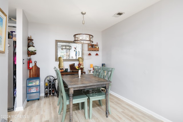 dining area with light hardwood / wood-style flooring and a chandelier