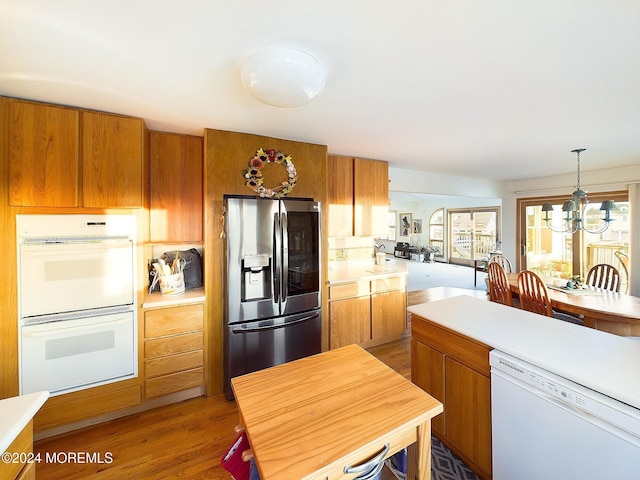 kitchen featuring pendant lighting, white appliances, dark hardwood / wood-style floors, and a notable chandelier