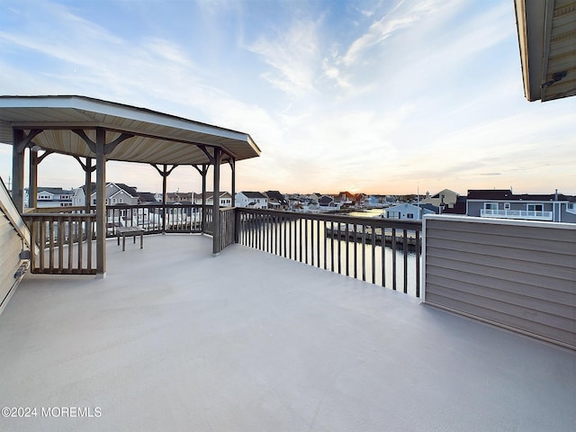 patio terrace at dusk featuring a gazebo and a water view