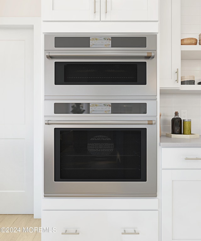 room details featuring white cabinets, double oven, and backsplash