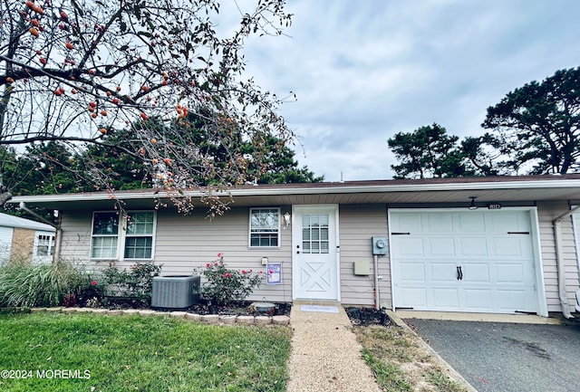 single story home with a garage, a front lawn, and central AC