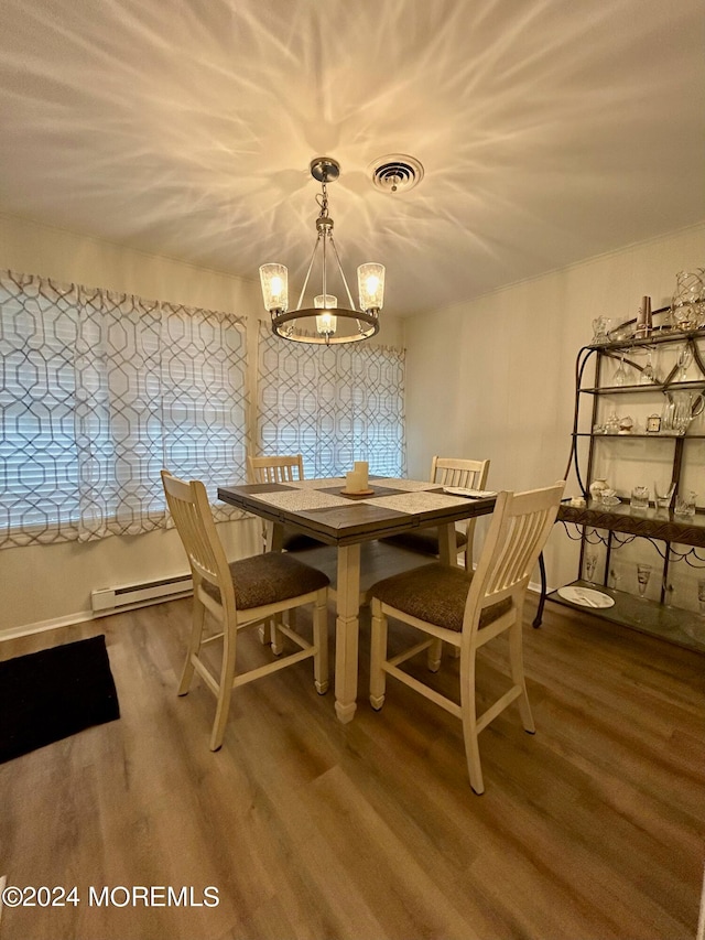 dining area with hardwood / wood-style floors, a baseboard heating unit, and a notable chandelier