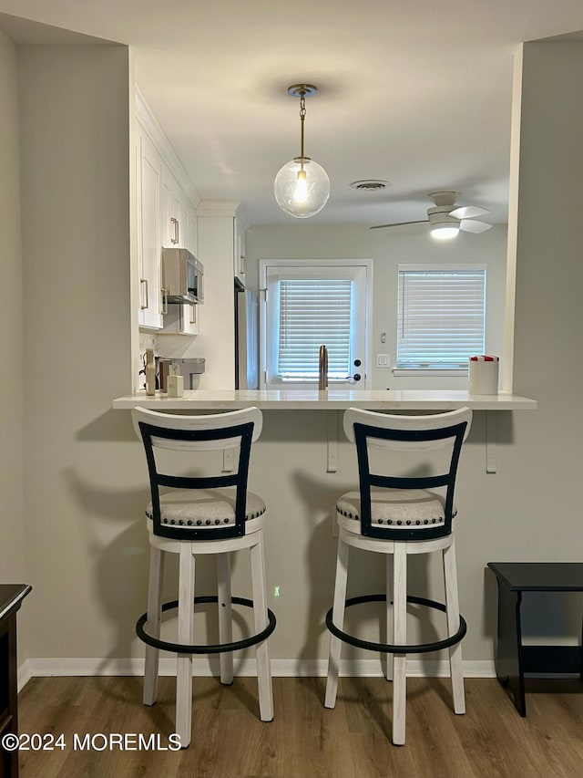 kitchen featuring white cabinets, appliances with stainless steel finishes, a kitchen breakfast bar, and dark hardwood / wood-style flooring