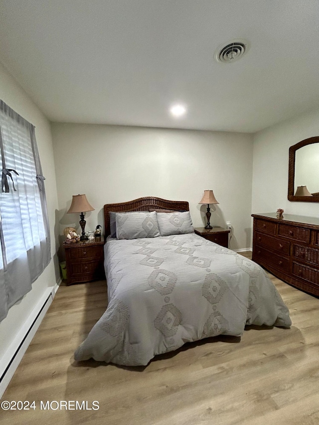 bedroom featuring baseboard heating and light hardwood / wood-style flooring