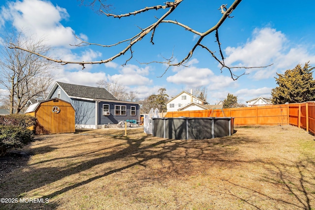 view of yard featuring an outbuilding, a shed, a fenced backyard, and a fenced in pool