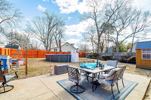 view of patio / terrace featuring an outdoor structure, outdoor dining area, a fenced backyard, and a fenced in pool