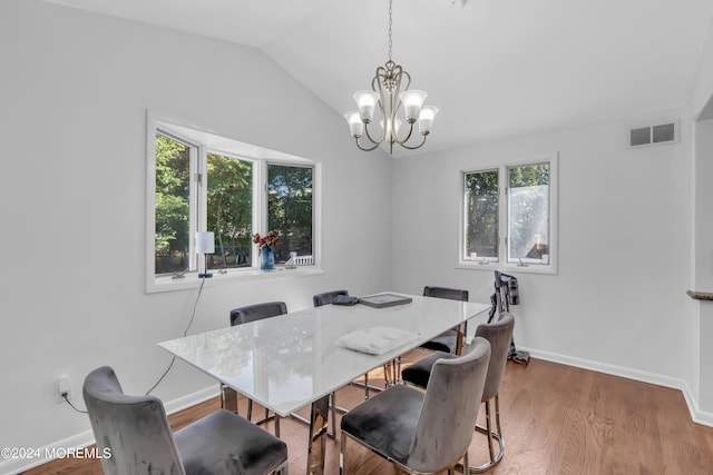 dining room with lofted ceiling, hardwood / wood-style flooring, a notable chandelier, and a wealth of natural light