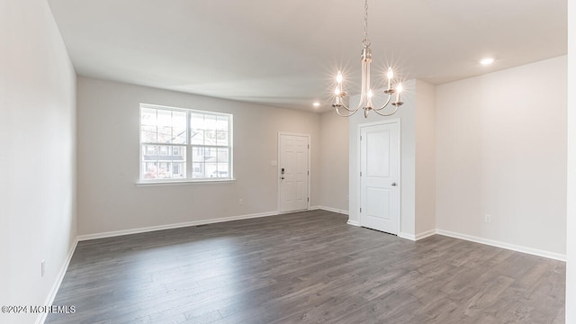 spare room featuring dark hardwood / wood-style floors and a chandelier