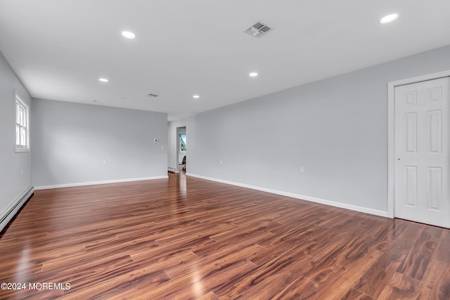 spare room with dark hardwood / wood-style floors and a baseboard heating unit