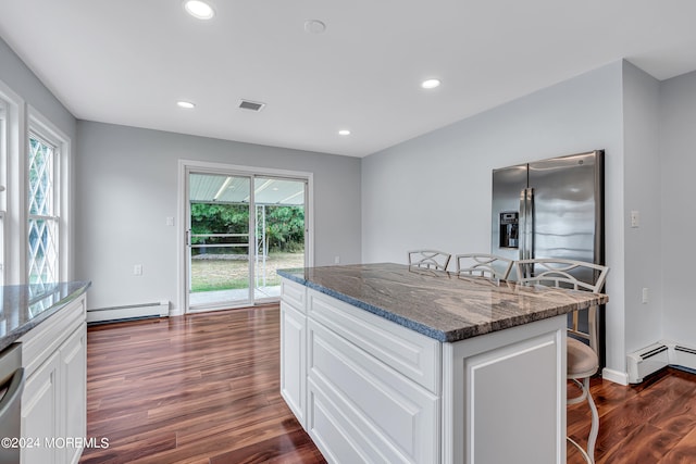 kitchen with a wealth of natural light, white cabinetry, dark hardwood / wood-style flooring, and a breakfast bar