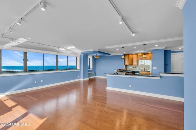 unfurnished living room with track lighting, hardwood / wood-style floors, a water view, and a wall unit AC