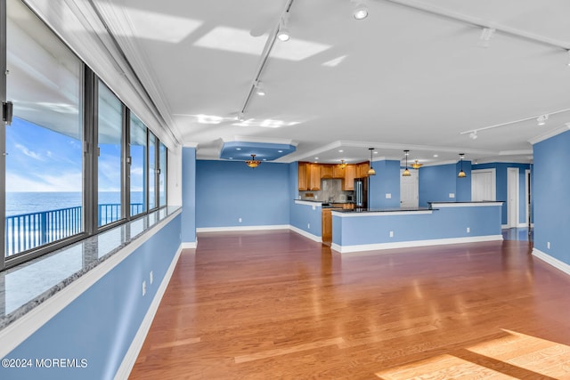 unfurnished living room with light hardwood / wood-style floors, ornamental molding, a water view, and rail lighting