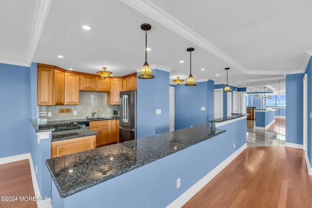 kitchen with light wood-type flooring, hanging light fixtures, stainless steel refrigerator, dark stone counters, and crown molding