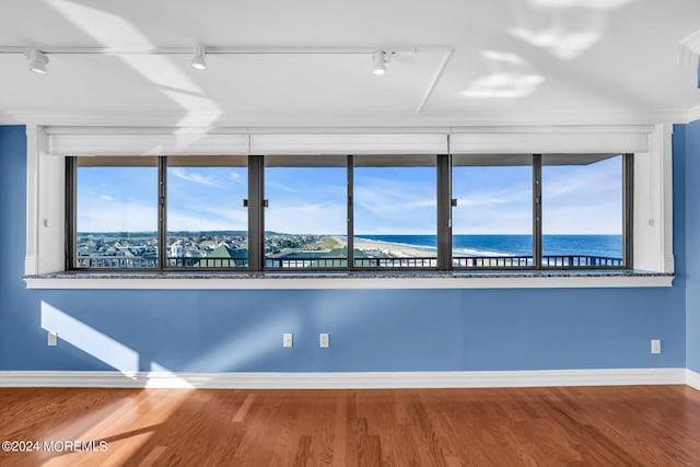 empty room with a water view, hardwood / wood-style floors, and track lighting