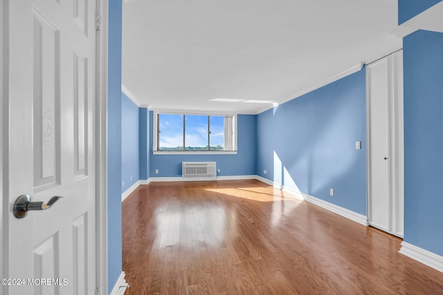 unfurnished room featuring ornamental molding, hardwood / wood-style flooring, and a wall mounted AC