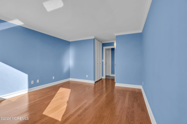 empty room featuring wood-type flooring and crown molding