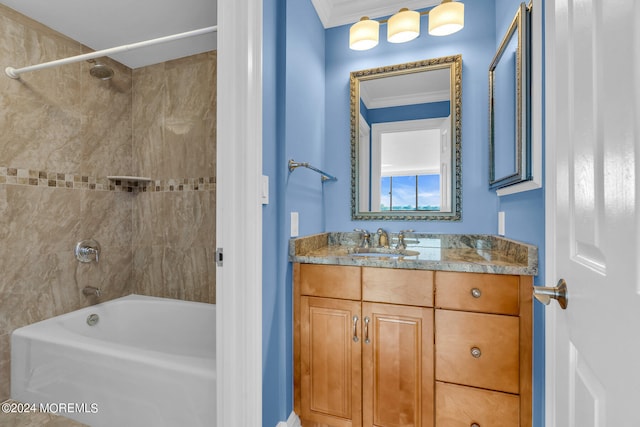 bathroom with crown molding, vanity, and tiled shower / bath