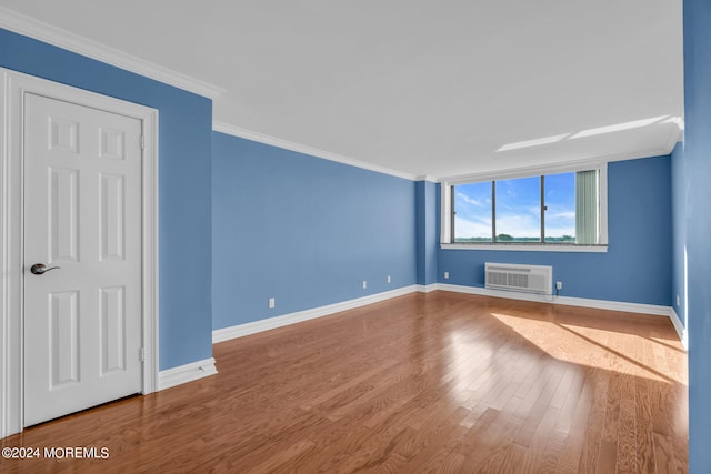 empty room with crown molding, a wall unit AC, and hardwood / wood-style flooring