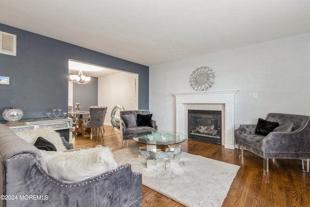 living room featuring a tile fireplace, wood-type flooring, and a notable chandelier