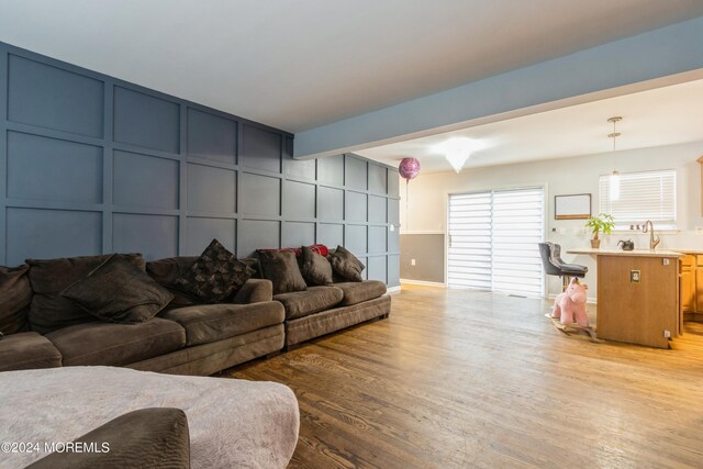 living room featuring light hardwood / wood-style floors, beamed ceiling, and sink