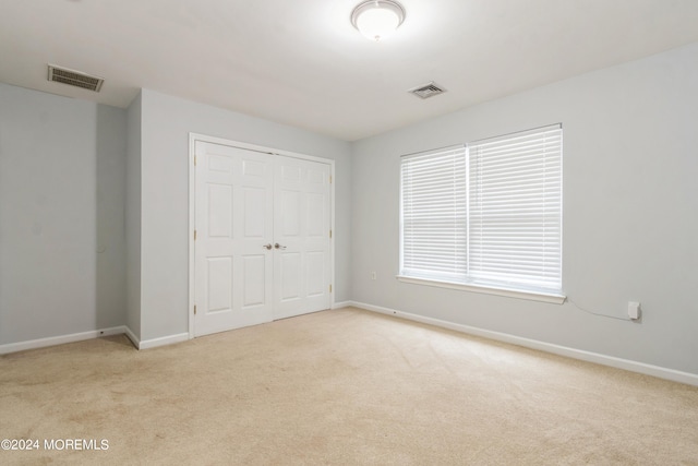 unfurnished bedroom featuring light colored carpet and a closet