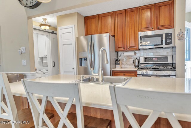 kitchen featuring a textured ceiling, stainless steel appliances, sink, and decorative backsplash