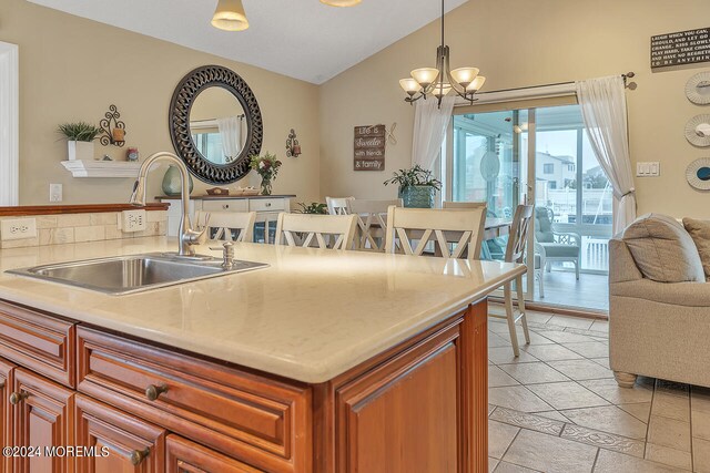 kitchen featuring pendant lighting, a breakfast bar area, sink, lofted ceiling, and an inviting chandelier