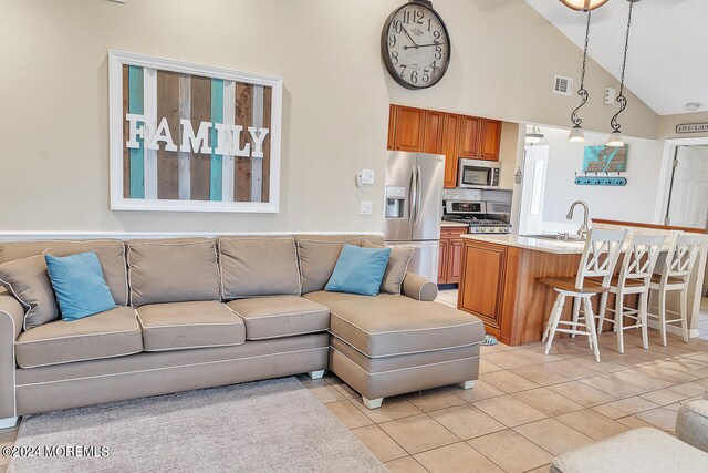 tiled living room with sink and high vaulted ceiling