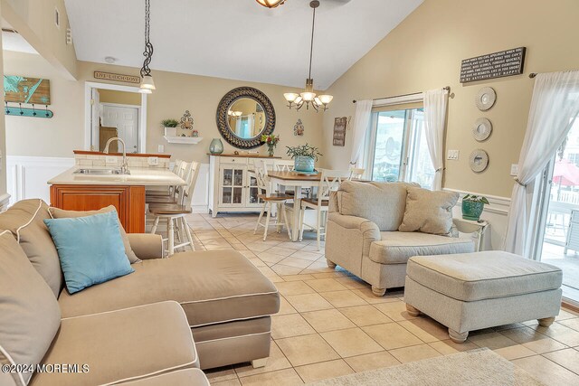 tiled living room with high vaulted ceiling, an inviting chandelier, and sink