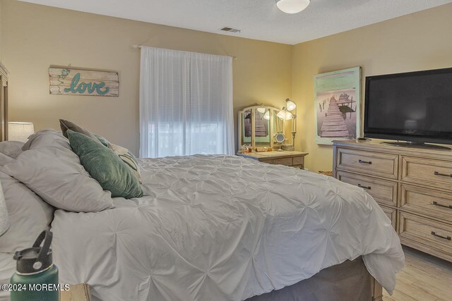 bedroom with light wood-type flooring and a textured ceiling