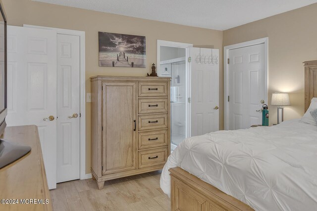 bedroom with light wood-type flooring and connected bathroom