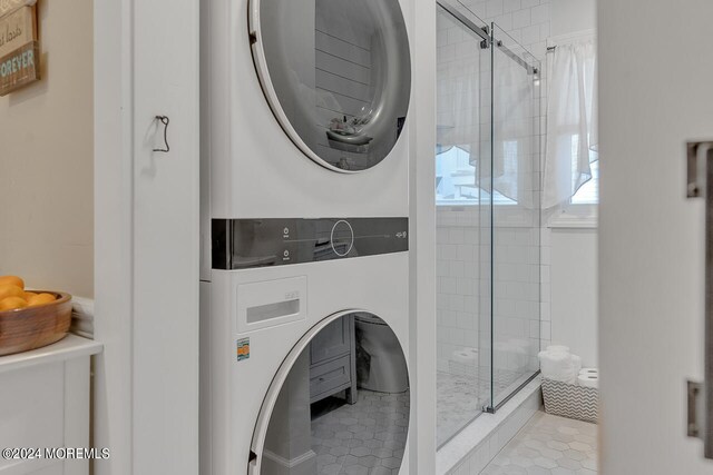 washroom with stacked washer and dryer and light tile patterned flooring