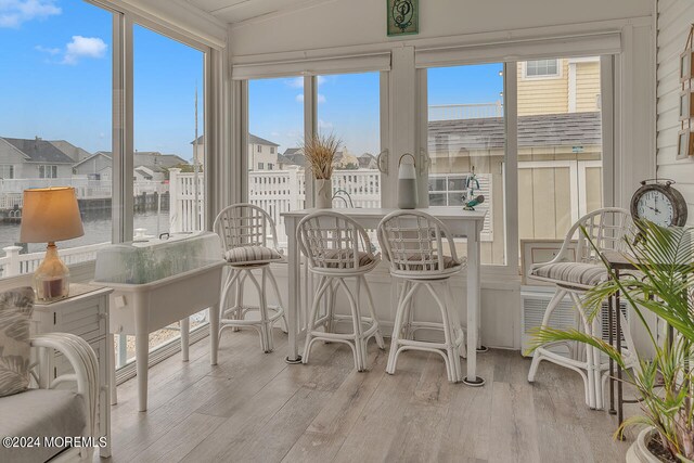 sunroom featuring a water view and lofted ceiling