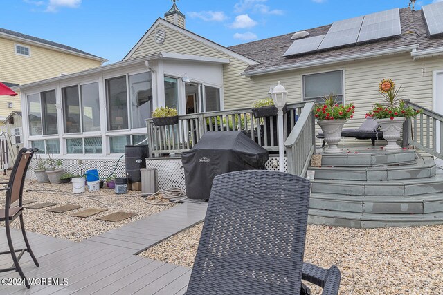 rear view of property with a wooden deck and a sunroom