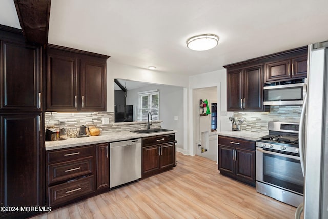 kitchen featuring decorative backsplash, light hardwood / wood-style floors, sink, and appliances with stainless steel finishes