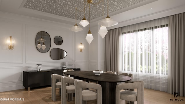 dining room featuring light wood-type flooring, a healthy amount of sunlight, ornamental molding, and a raised ceiling