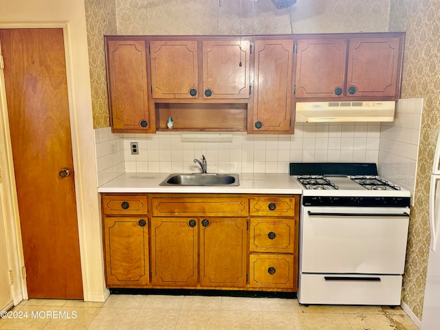 kitchen with white range oven, decorative backsplash, sink, and light tile patterned floors