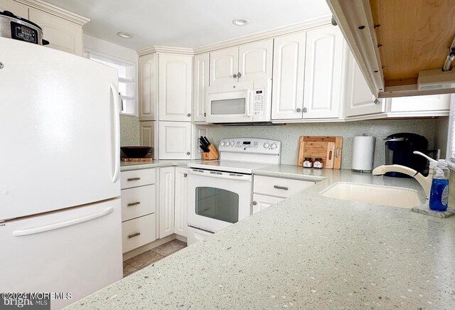 kitchen featuring white appliances, sink, and white cabinets