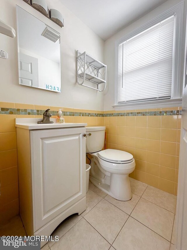 bathroom with tile walls, tile patterned flooring, vanity, and toilet