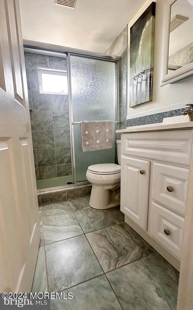 bathroom featuring vanity, toilet, and a shower with door